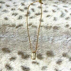 Gold necklace with rectangle pendant featuring sun, moon and star